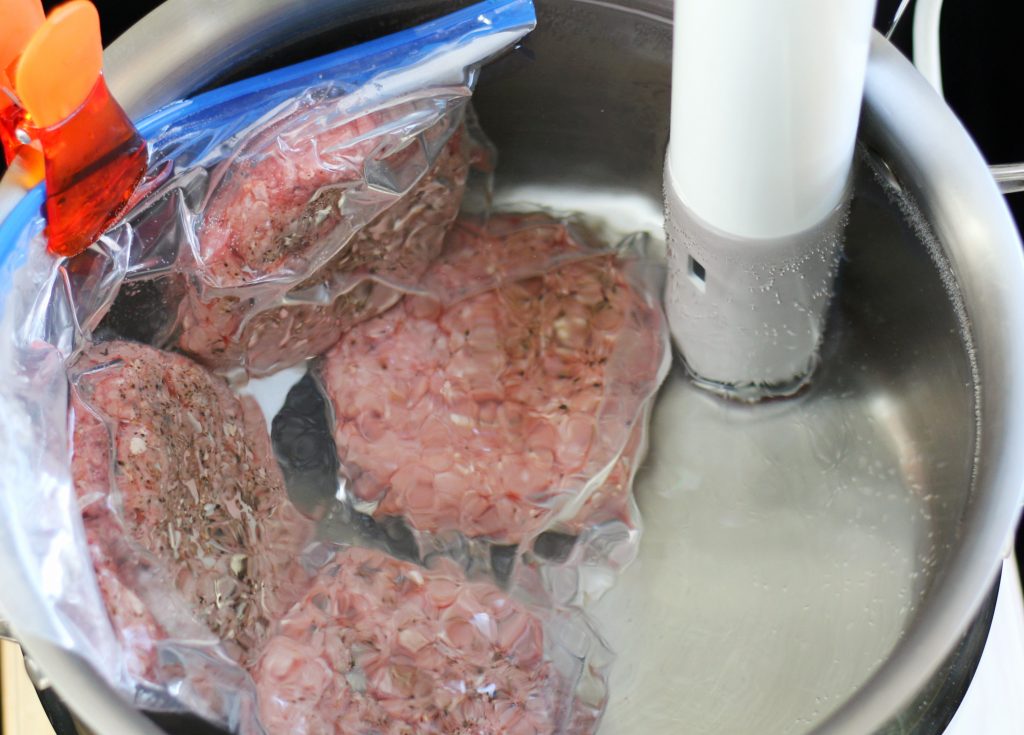 overhead of sous vide burgers in pot of water with circulator