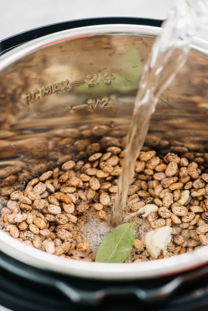 Pouring water into Instant Pot Pinto Beans Vertical