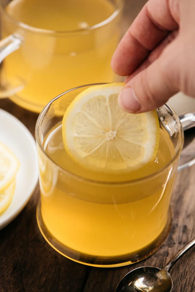 Hot toddy drink with lemon wheel in hand