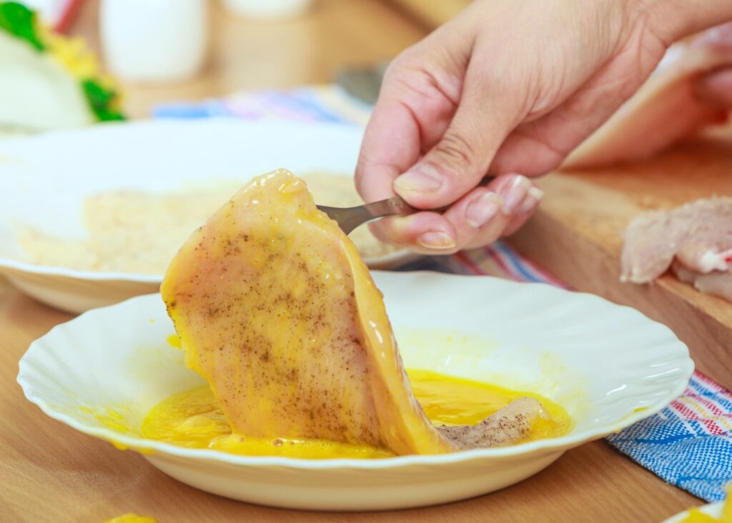Chicken cutlet dipping in egg wash